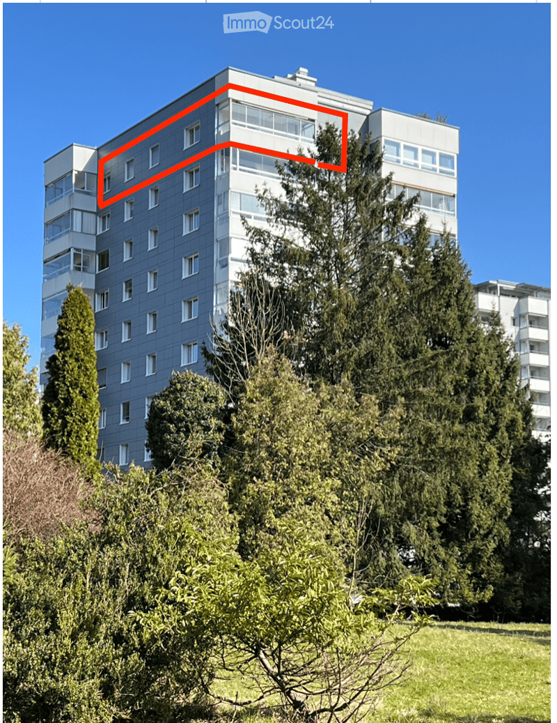 Multi-story residential building with a modern facade, large windows, and surrounding greenery.
