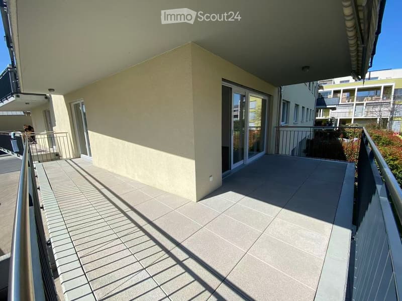 Balcony with tiled floor, metal railings, and glass doors leading to the interior.