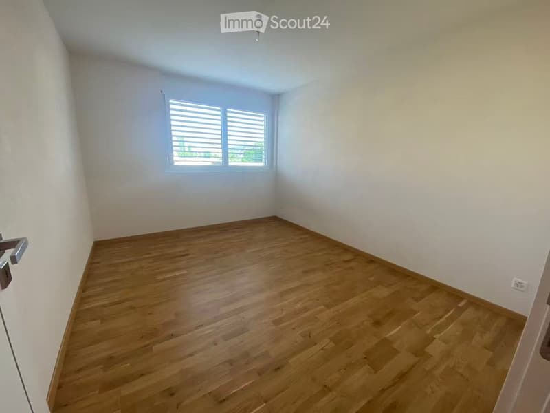Empty room with wooden flooring, white walls, and a window with blinds. No furniture or equipment is present.
