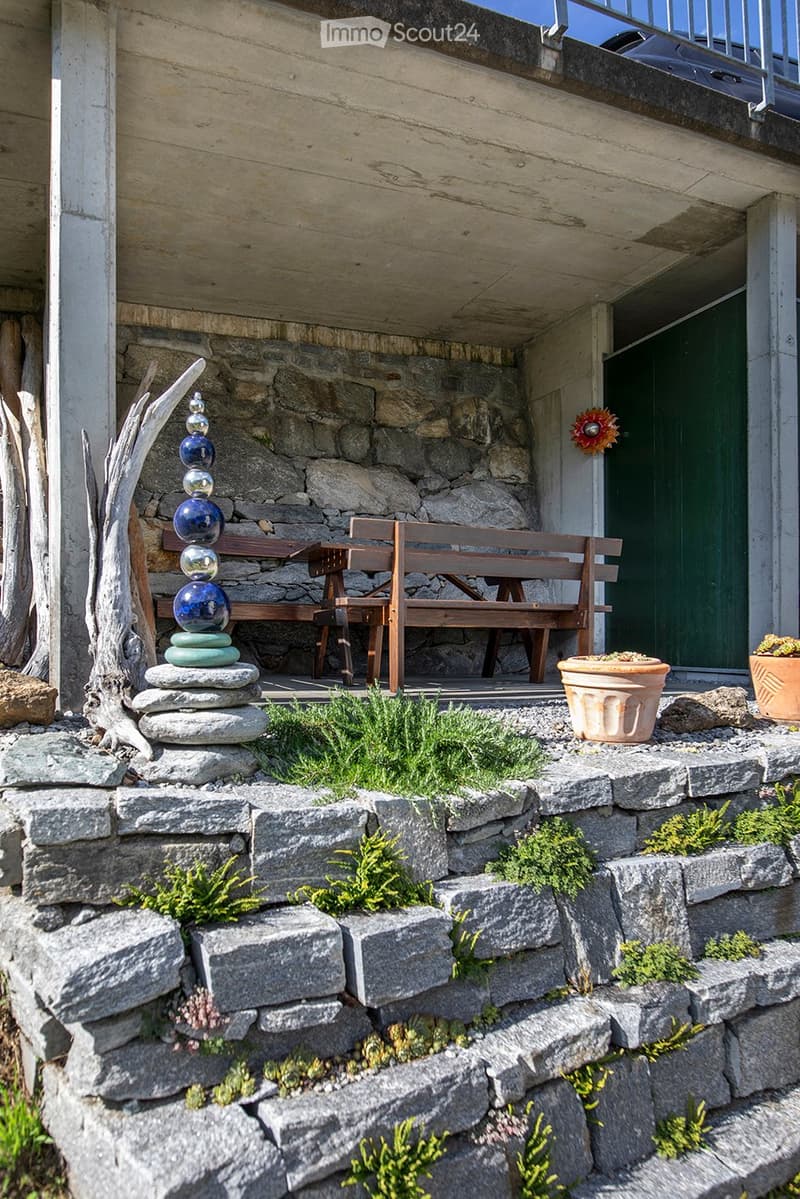Stone stairs, wooden bench, decorative glass columns, green door, plants, small garden