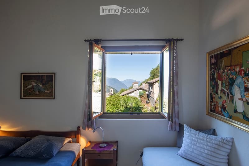 room with double bed, desk with lamp, painting, window with valley view