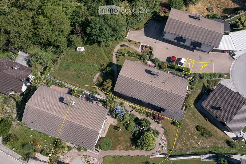 Two houses with driveways and gardens, with 2 parking spots near one of the houses