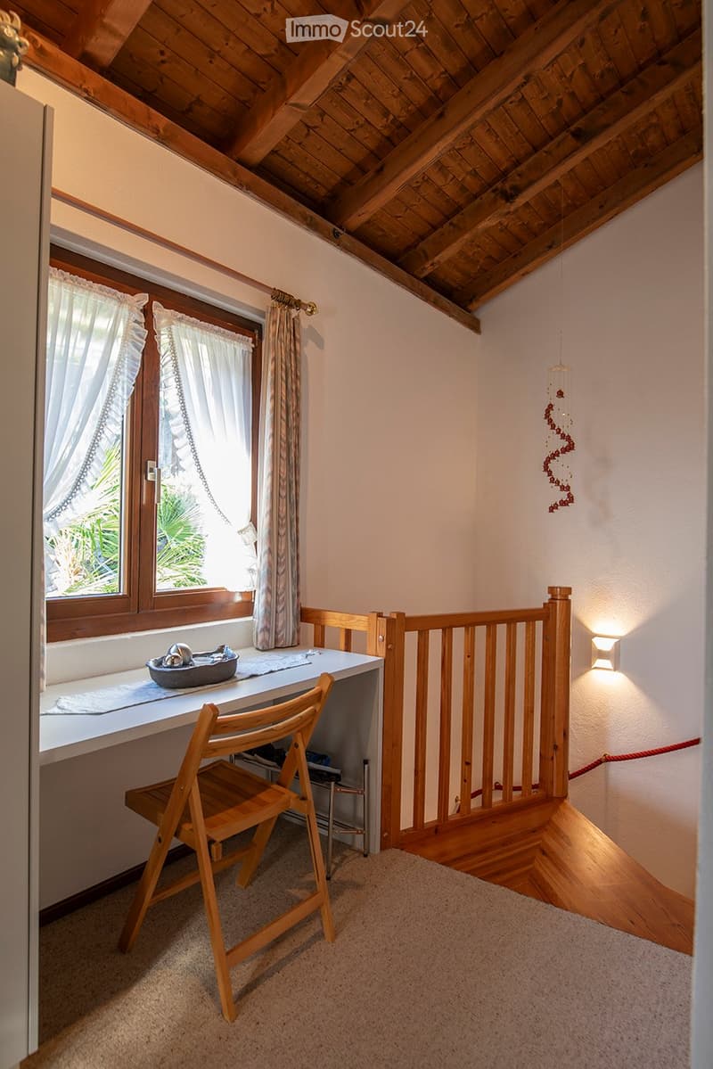 Desk with folding chair, wooden railing, stairs to basement, double window with curtains