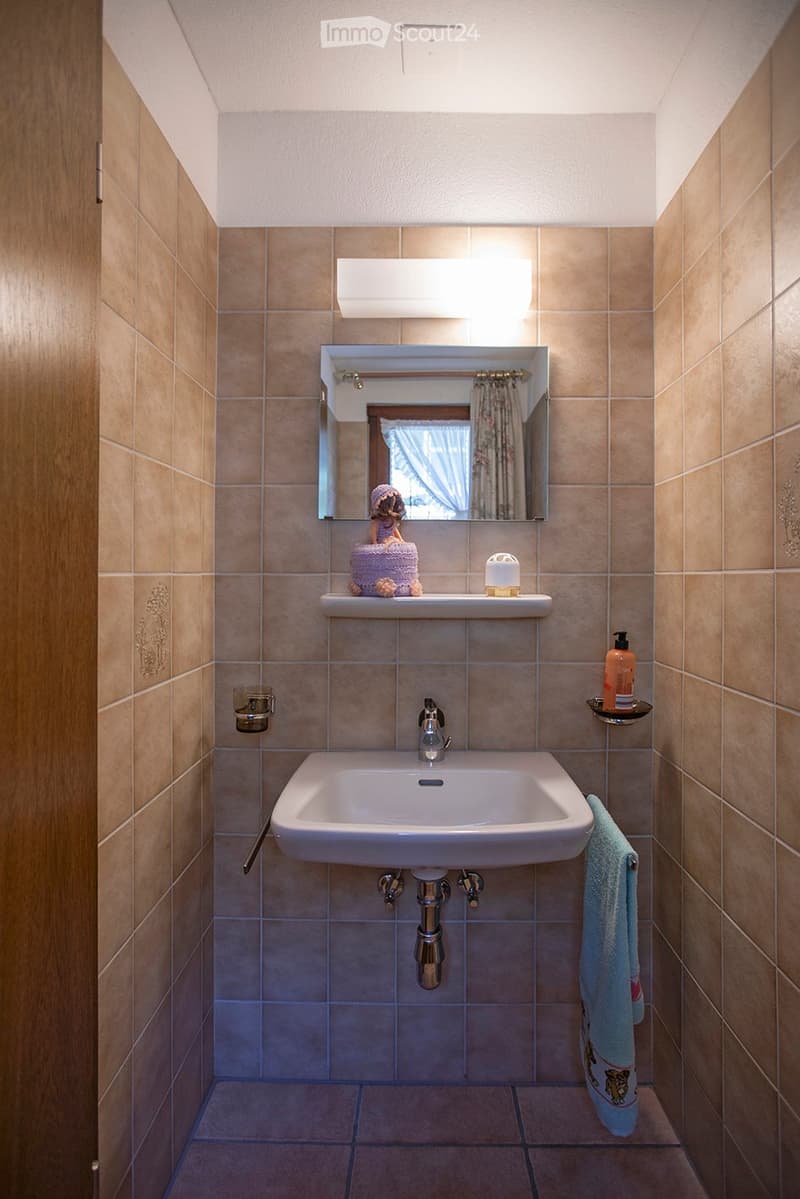 tiled walls, mirror above sink, wash basin, shelf with figurines, towel