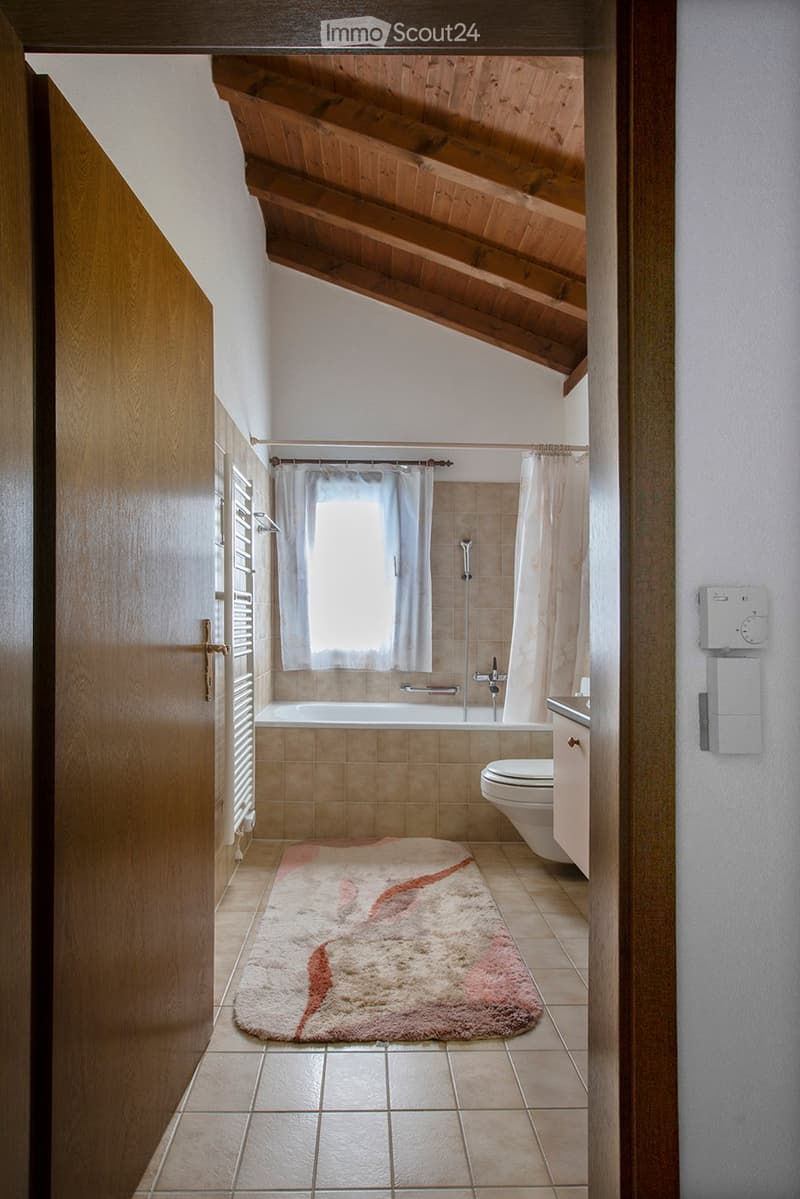 Bathroom: bathtub, white toilet, sink, window, tiled floor, wooden ceiling