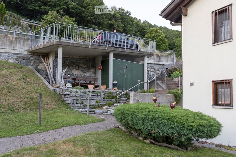 House exterior with a parking place on an elevated level, a green door to the parking place, and steps leading up to the entrance.