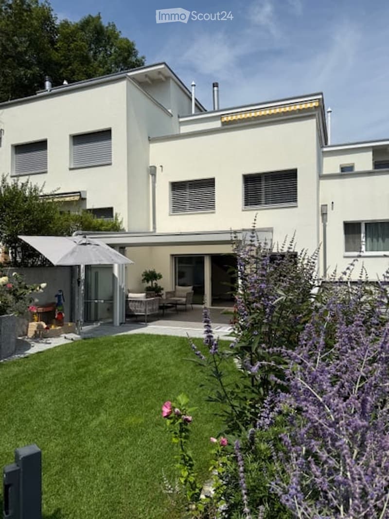 modern house, white exterior, large windows, glass patio doors, awning, garden, patio furniture, umbrella, greenery