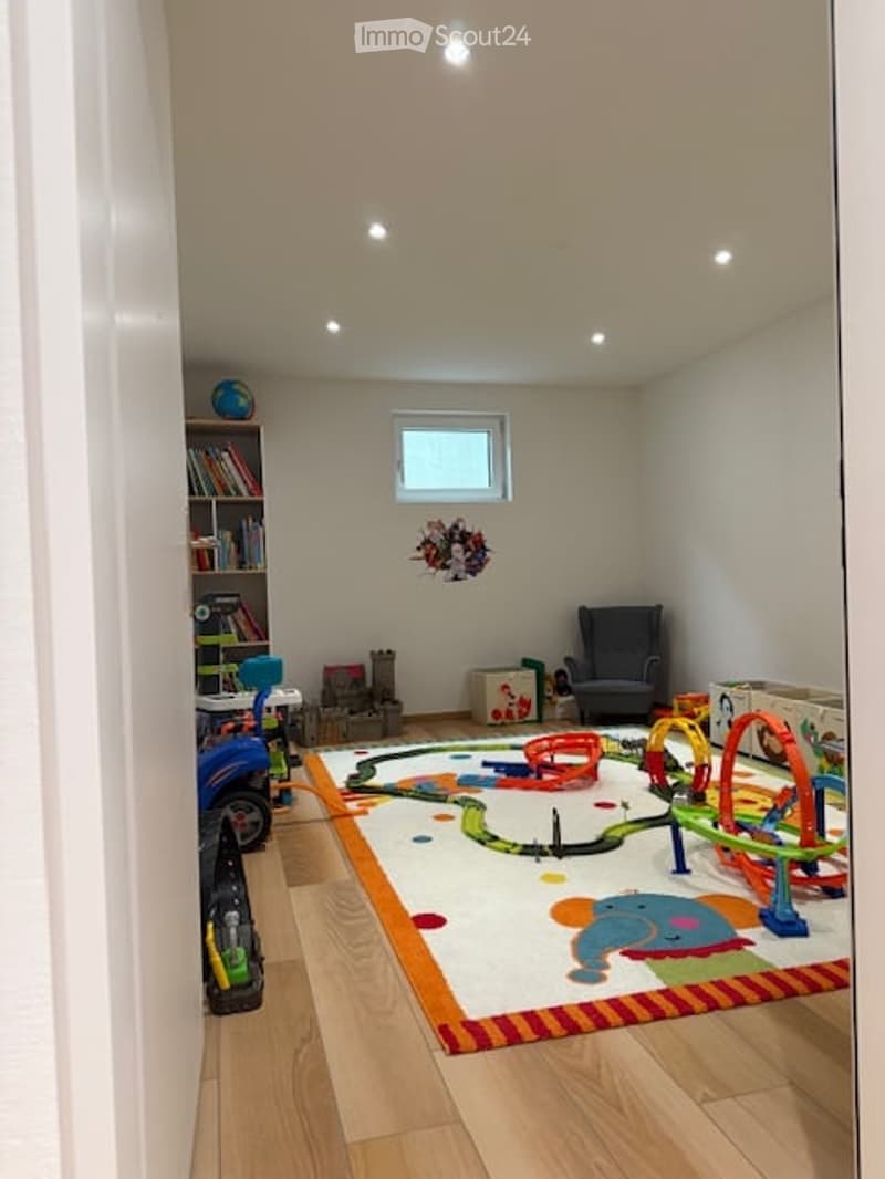 Playroom with toys, toys on the floor, chair, bookshelf, small window