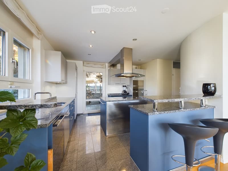 Modern kitchen with white cabinets, granite countertops, stainless steel appliances, and blue island with bar stools.