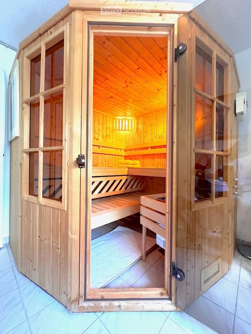 A wooden sauna with glass-paneled doors, wooden benches, and a warm, inviting interior.