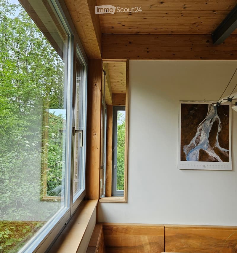 Corridor / Hallway. A modern hallway with wooden ceilings and walls, large windows with wooden frames, and a calendar on the wall.