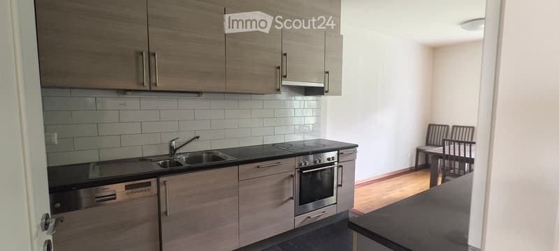 Modern kitchen with wooden cabinets, stainless steel appliances, and a small dining area with a table and chairs.