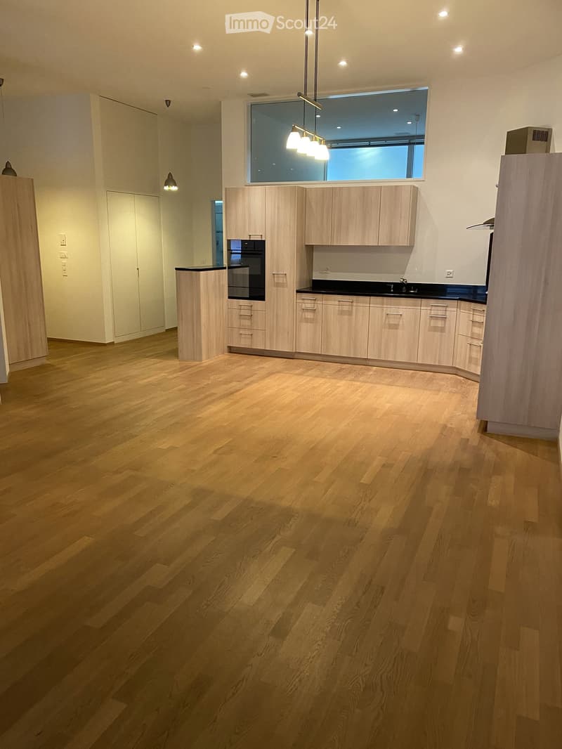 modern kitchen with wooden cabinets, black countertops, large windows, wooden floor