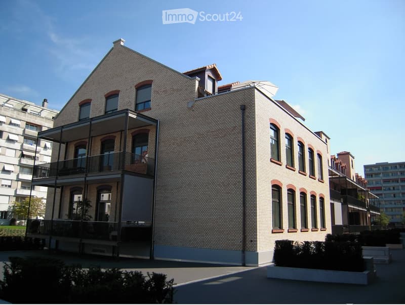 3 story brick house, multiple windows, balcony, garden