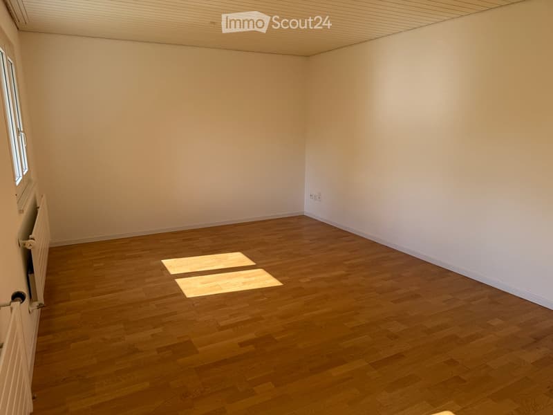 Empty room with wooden flooring and white walls, featuring a window and radiator on one side.