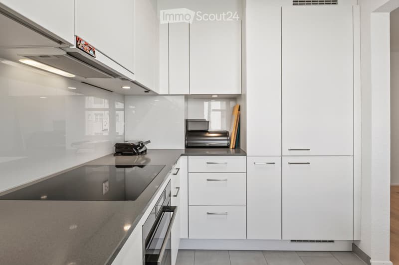 Modern kitchen with white cabinets, stainless steel appliances, and a sleek countertop.