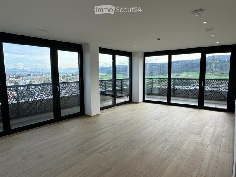 Empty room with large sliding glass doors leading to a balcony, wooden flooring, and a scenic mountain view.