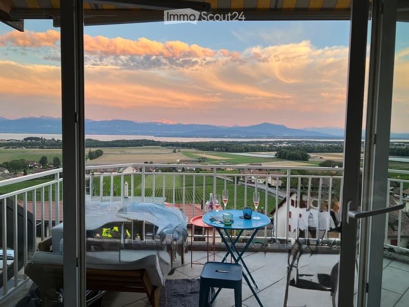 Balcony with scenic view of mountains and countryside, furnished with a small table, chairs, and a stool.