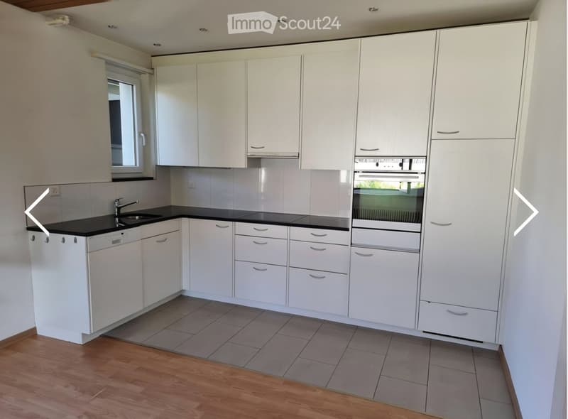 Modern kitchen with white cabinets, black countertops, and a built-in oven and dishwasher.