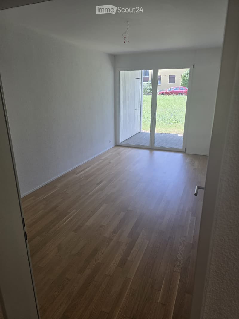 Empty room with wooden flooring, white walls, and a large sliding glass door leading to an outdoor area.
