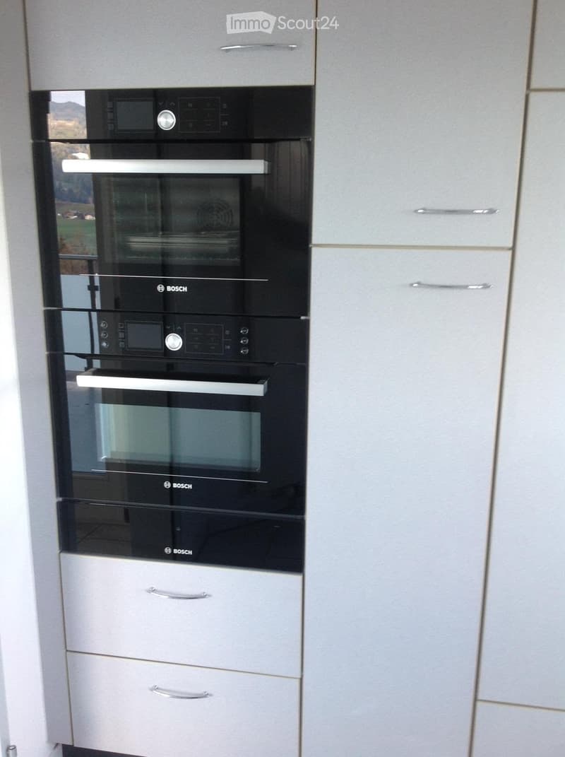 Modern kitchen with Bosch ovens and white cabinets.