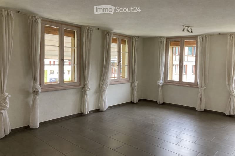 Empty room with tiled floor, large windows with curtains, and recessed lighting fixture.