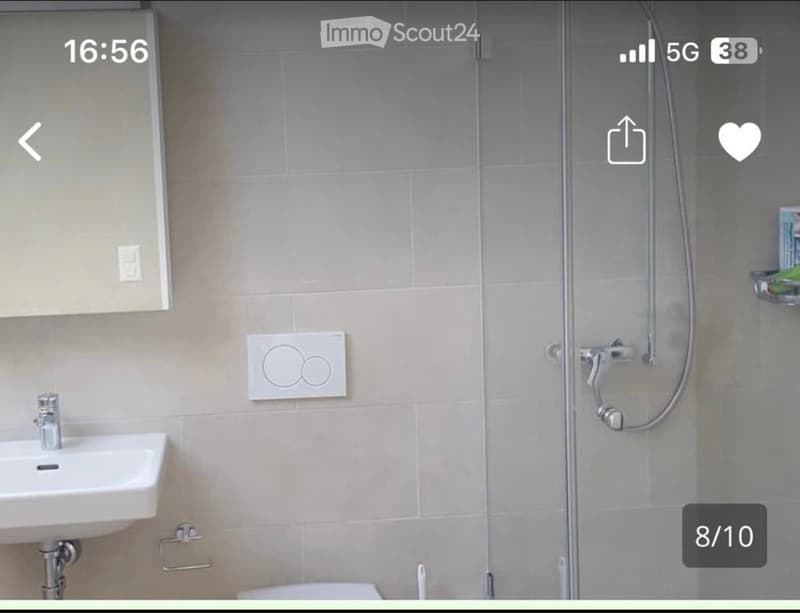 Modern bathroom with a white sink, chrome faucet, glass shower enclosure, and a towel rack. Light beige tiles and sleek fixtures.