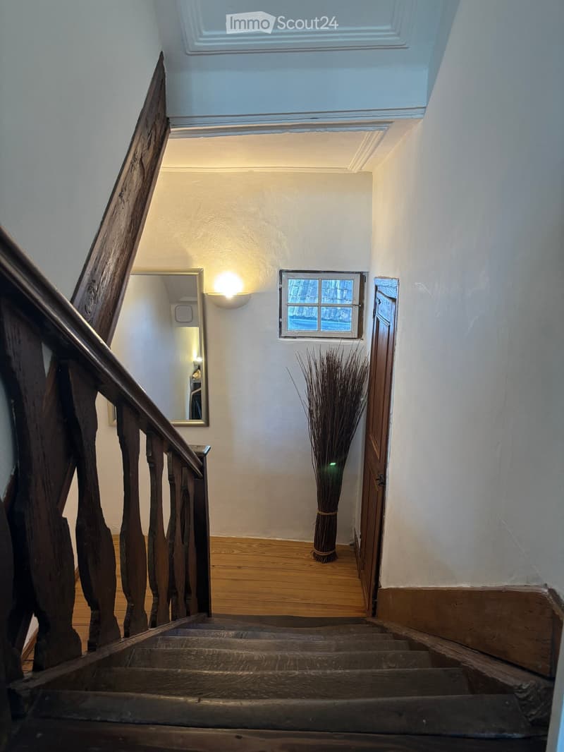wooden stairs, white walls, wooden floor, light, mirror, small window, wooden door, vase with plant