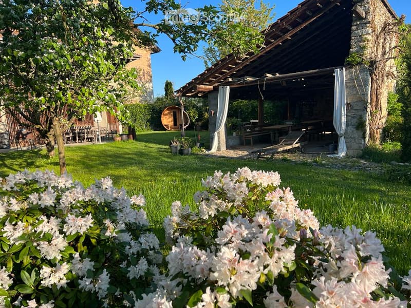 well-maintained green lawn, white flowers, wooden house in background, outdoor seating area
