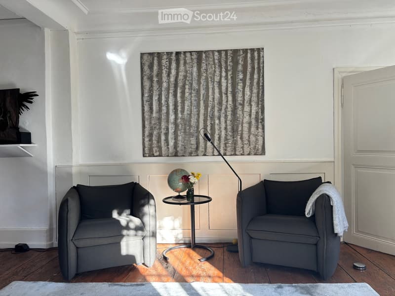 modern style, grey armchairs, side table with globe, floral vase, lamp, wall art, wooden floor, white rug