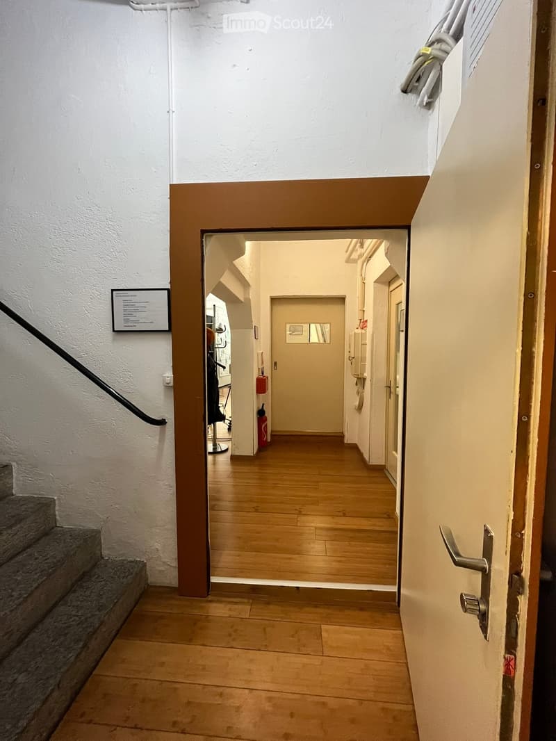 Open entrance door, wooden floor, staircase, hallway leading to doors