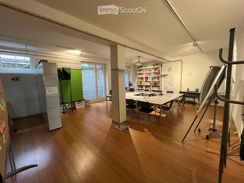 large open room with hardwood floors, large windows, desk, chairs, bookcase, projector, whiteboards