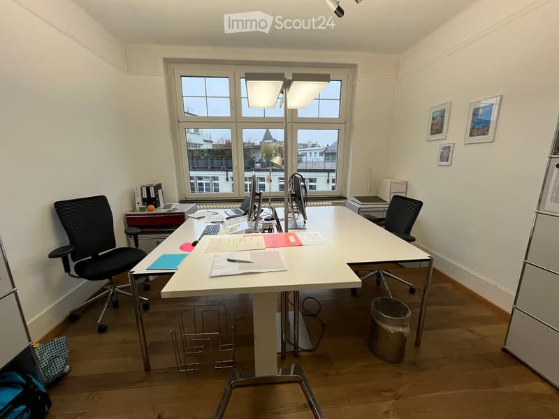 empty office room with desks, chairs, and framed pictures on the wall