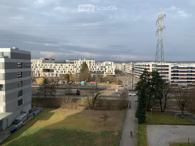 Aerial view of a modern residential complex with multiple buildings, parking areas, and open green spaces.