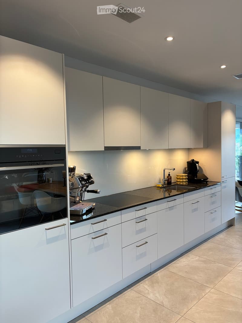 Modern kitchen with white cabinets, stainless steel appliances, and a black countertop.