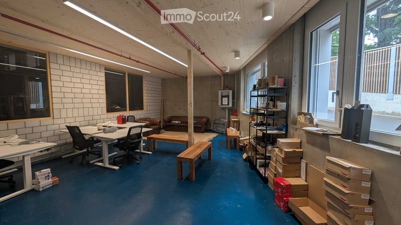 Office space with modern furniture, including a white table with chairs, a sofa, wooden benches, shelves, and various office supplies.