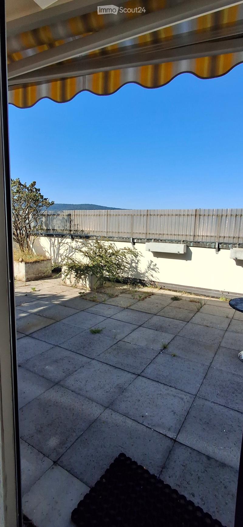 Terrace with tiled floor, small plants, and a view of the sky and surrounding area.