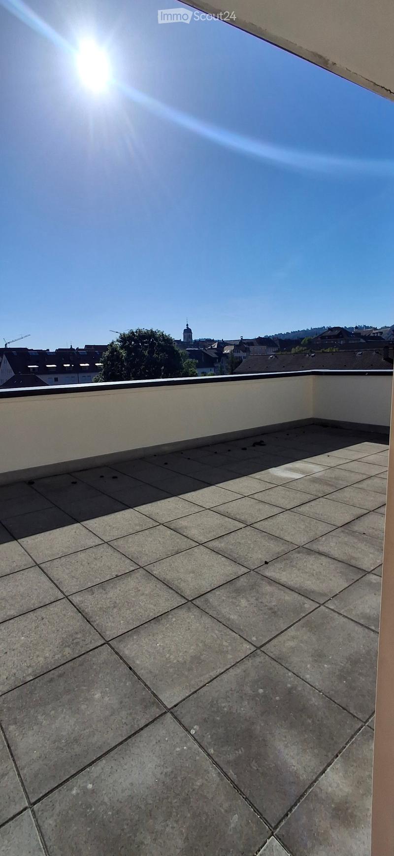Roof terrace with tiled flooring, low parapet wall, and cityscape view in the background.