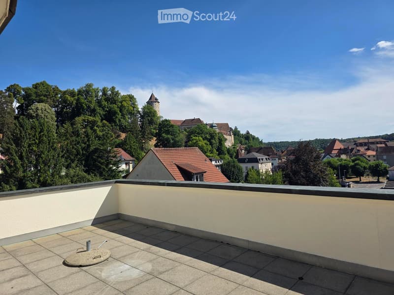 Flat rooftop terrace with tiled surface, low parapet wall, and scenic view of town and castle.