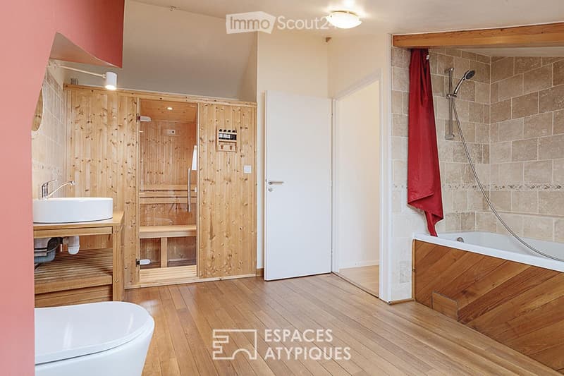 Bathroom with wooden sauna, sink, bathtub, and shower. Features wooden flooring and warm lighting.