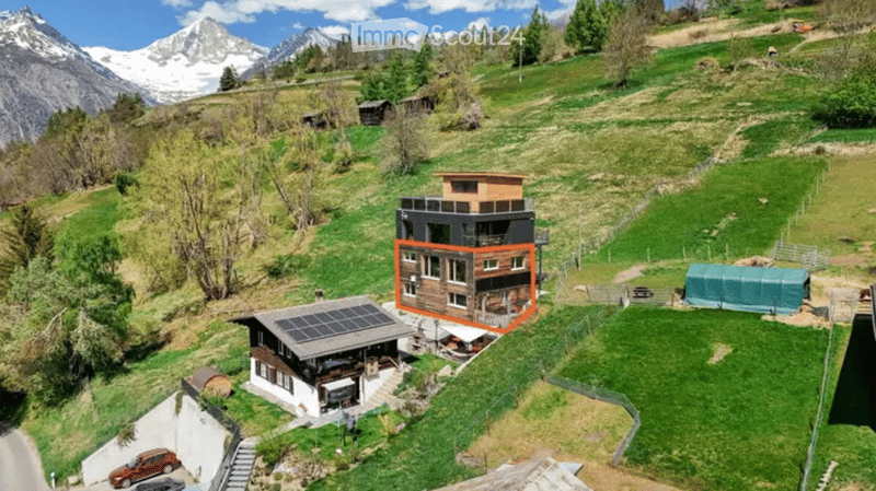 House with solar panels, wooden exterior, surrounded by green grass and mountains
