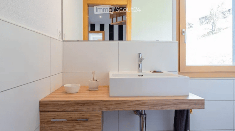 Bathroom with white sink, wooden countertop, white tiles, mirror, and wooden cabinet