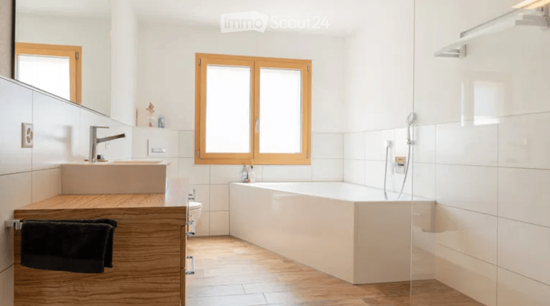 Bathroom with wooden floor, white tiles, bathtub, sink, mirror, toilet, towel rack