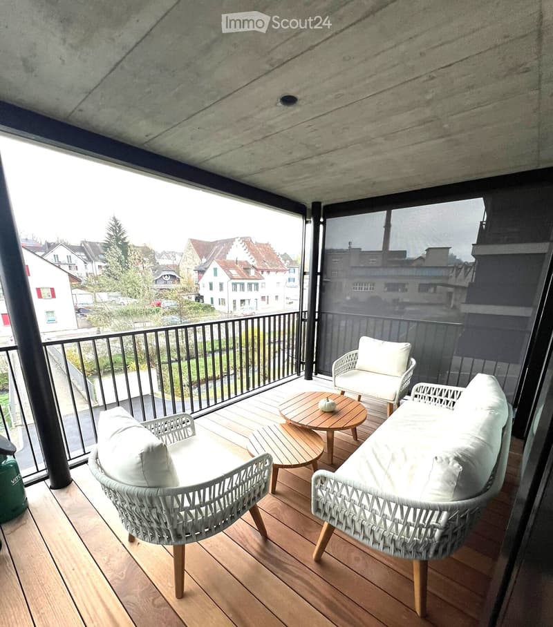 balcony with wooden floor, black railing, white wicker chairs, wooden coffee table, white cushions, black screen