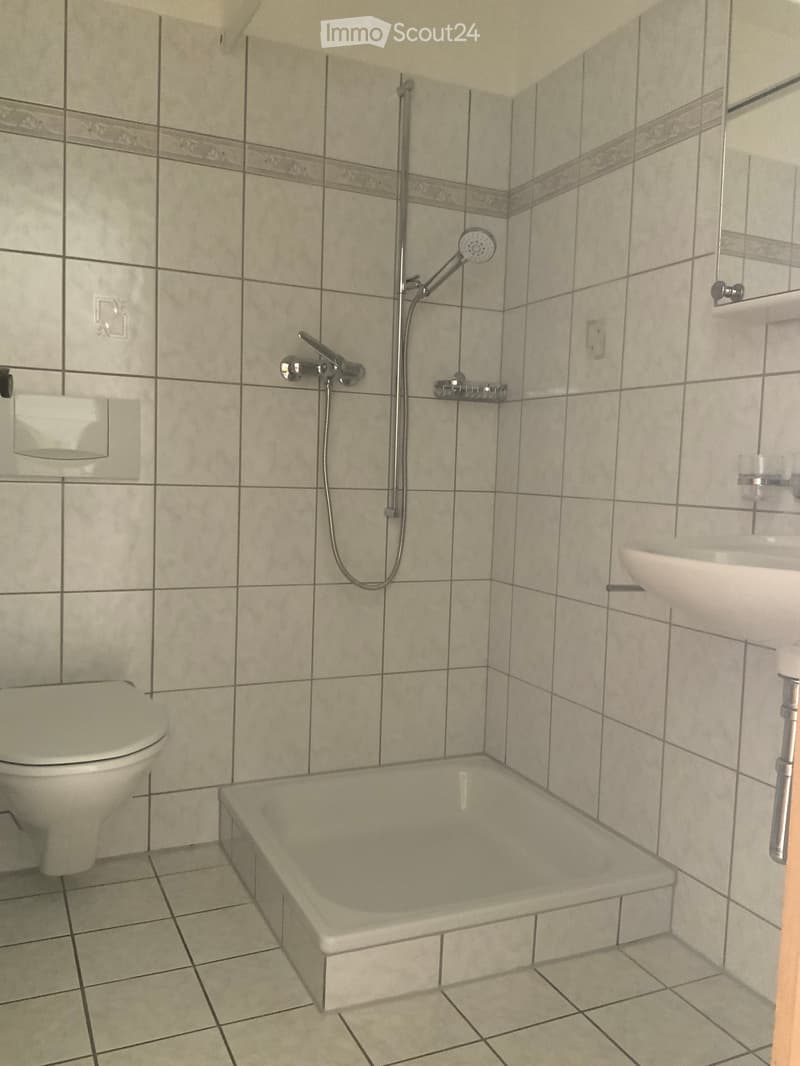 Bathroom with tiled walls and floor, featuring a bathtub, toilet, sink, and showerhead.
