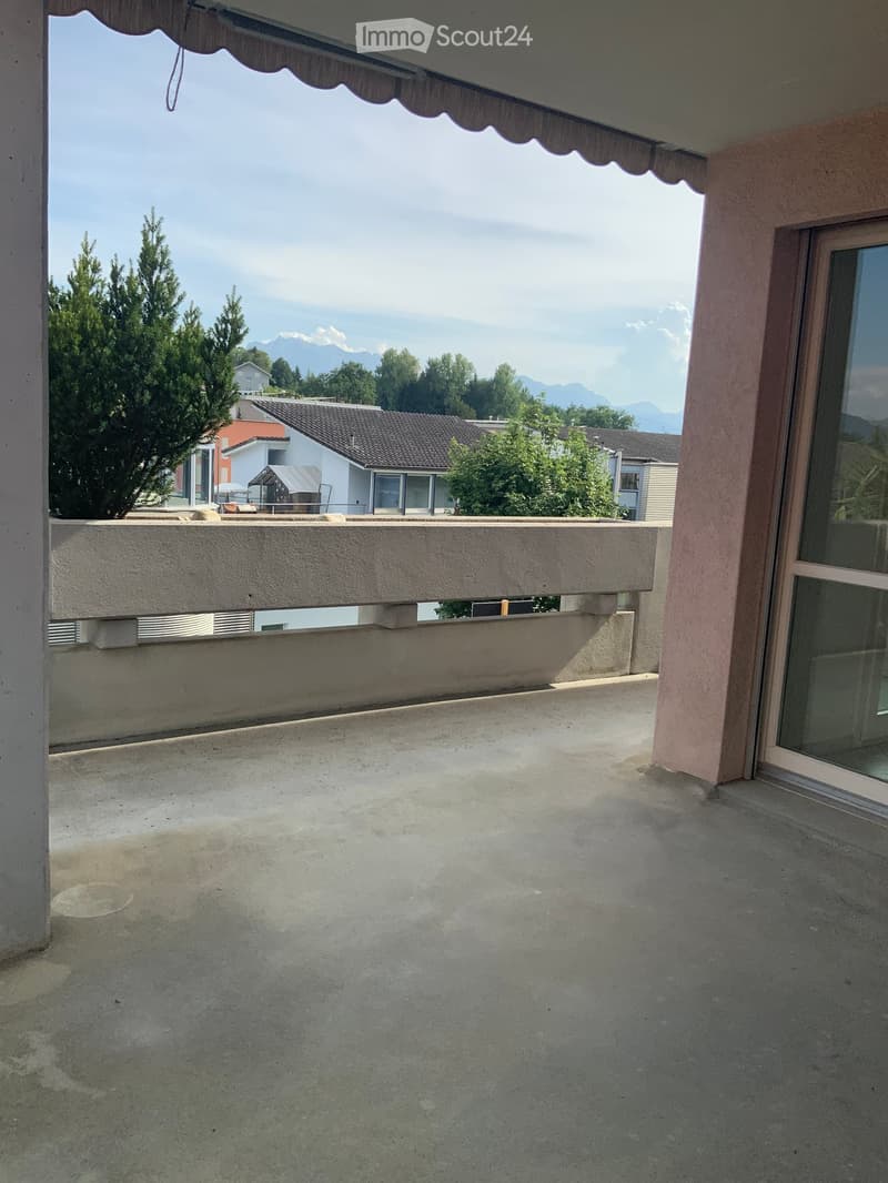 Balcony with concrete floor, low railing, and scenic mountain view in the background.