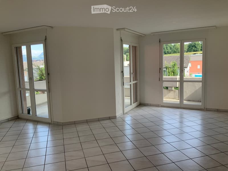 Empty room with tiled floor, large windows, and sliding glass doors leading to a balcony.