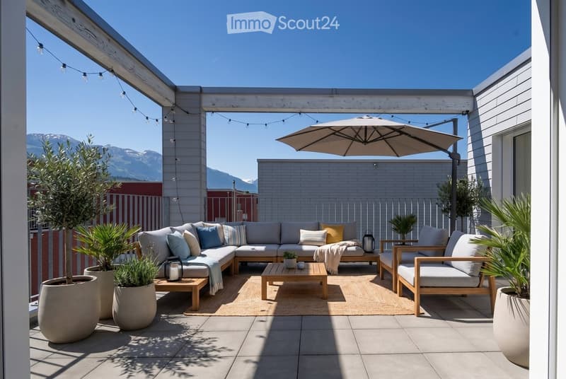 A modern outdoor patio with a sectional sofa, coffee table, armchair, umbrella, and potted plants, set against a backdrop of mountains.