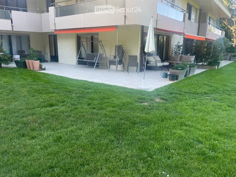 Well-maintained garden with a swing, outdoor seating, and potted plants.