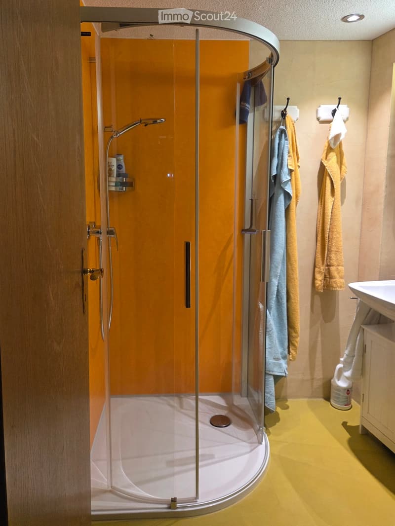 Modern bathroom with a walk-in shower, glass enclosure, towel rack, sink, and cabinet.